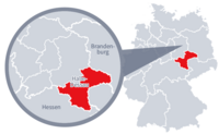 Diese Grafik zeigt eine Karte von Deutschland mit einer detaillierten Ansicht der Region Halle-Dessau. Halle-Dessau ist in Rot hervorgehoben und liegt im nördlichen Teil Deutschlands. Ein Lupensymbol vergrößert diesen Bereich, um die Lage genauer darzustellen.