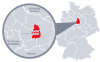 Diese Grafik zeigt eine Karte von Deutschland mit einer detaillierten Ansicht der Region Süd-Ost-Niedersachsen. Süd-Ost-Niedersachsen ist in Rot hervorgehoben und liegt im nördlichen Teil Deutschlands. Ein Lupensymbol vergrößert diesen Bereich, um die Lage genauer darzustellen.
